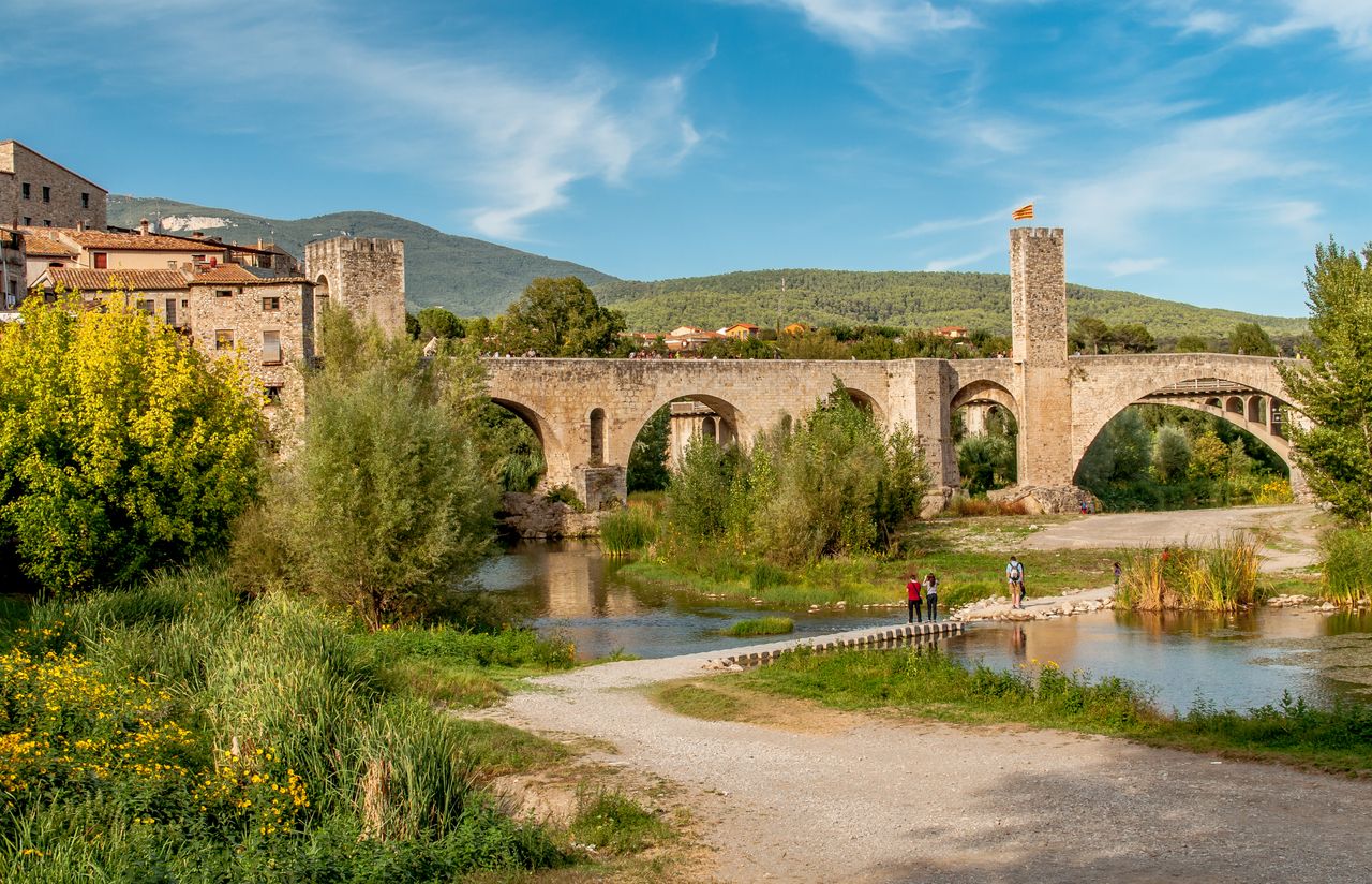 Picturesque view of Besalú's medieval bridge in summer, with scenic landscape and river.