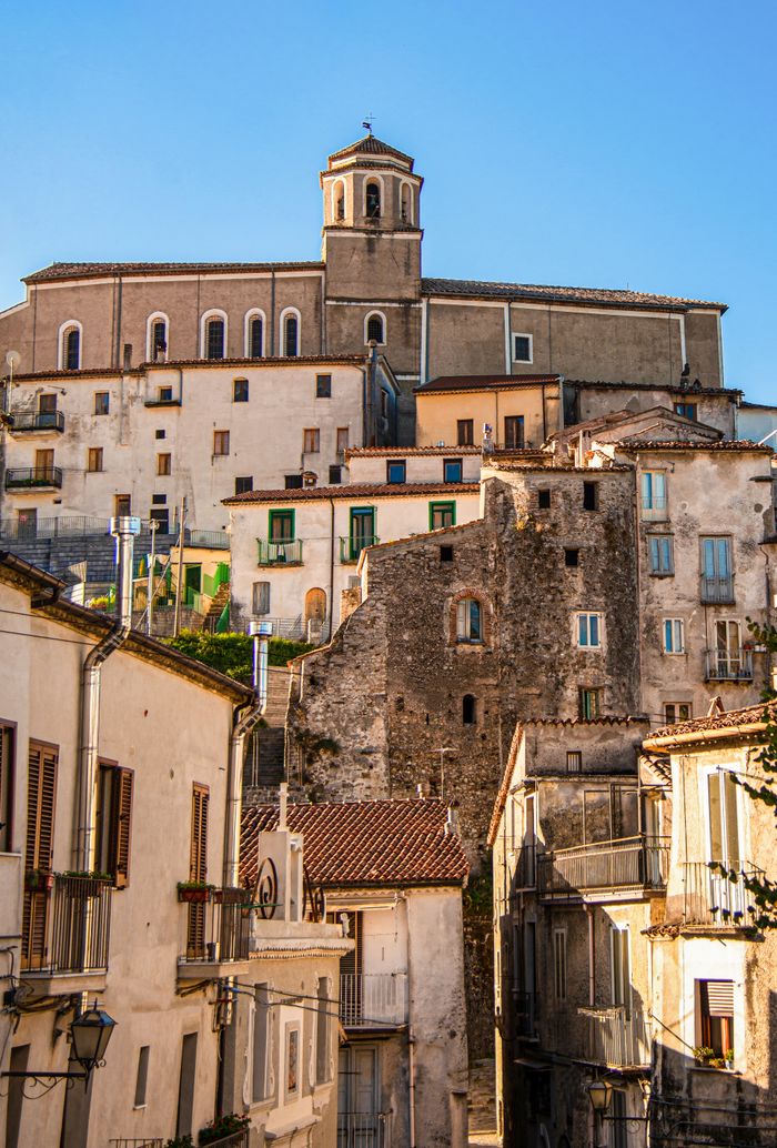 Captivating view of a historic Italian cathedral surrounded by charming urban architecture under a clear blue sky.