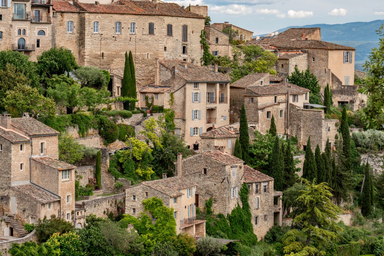 Picturesque view of a medieval village with stone houses and lush greenery in Provence, France.